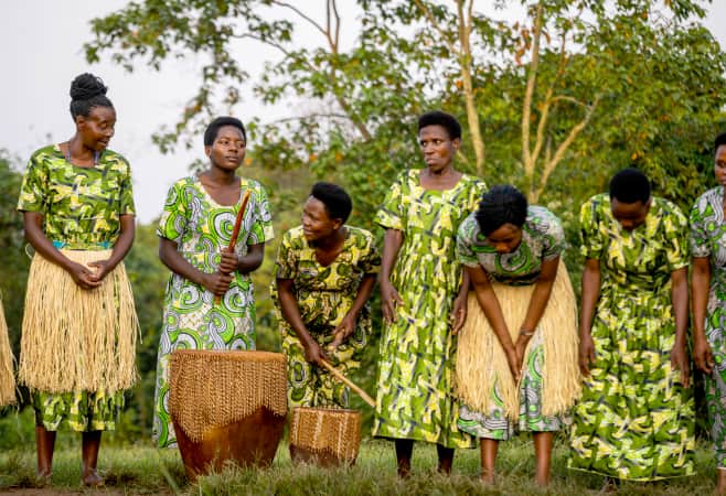 Women in coordinated patterned dresses on grass in rural Rwanda